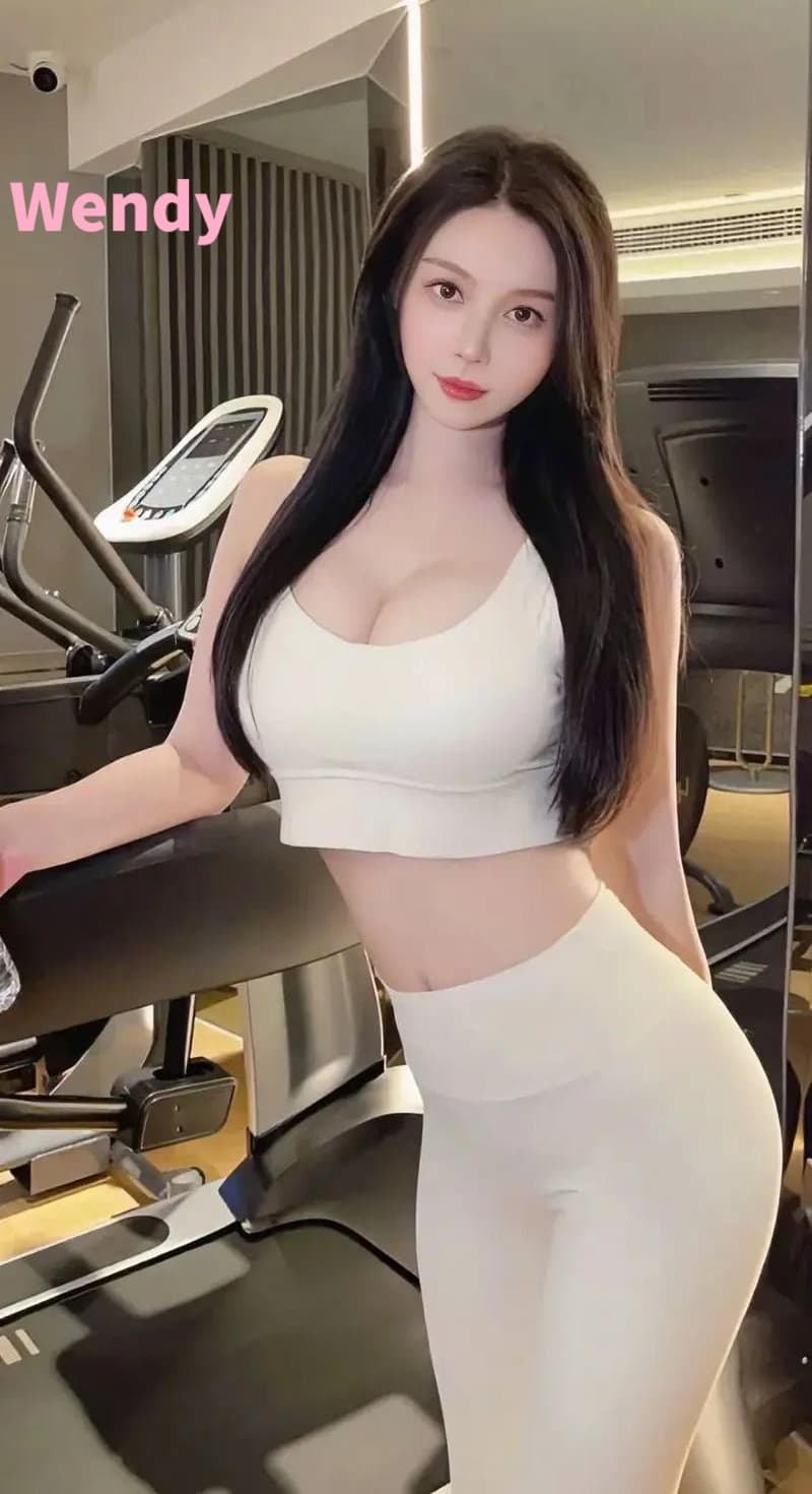 Woman with long dark hair in white athletic wear posing next to a gym treadmill.